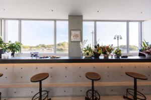 a bar with three stools at a counter with windows at urashima INN - GANGI - in Onomichi