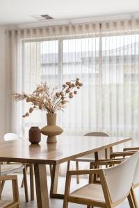 una mesa de comedor con sillas y un jarrón con flores en Modern Minimalistic Home en Perth