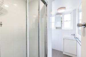 a white bathroom with a shower and a sink at Sunnie Belle, 2,3 Victoria Parade - Unit with water views and air conditioning in Nelson Bay