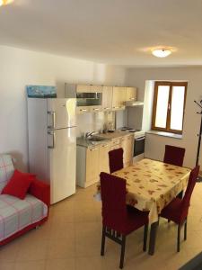 a kitchen with a table and chairs and a white refrigerator at Apartments with WiFi Susak, Losinj - 17303 in Susak