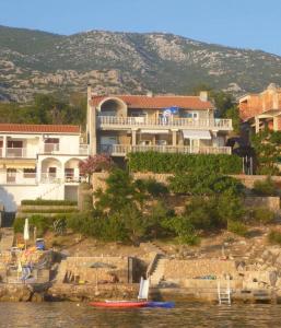 ein Haus auf einem Hügel mit einem Boot im Wasser in der Unterkunft Apartments by the sea Prizna, Senj - 17309 in Senj