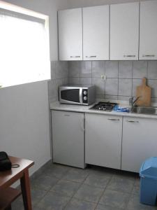 eine Küche mit weißen Schränken und einer Mikrowelle auf der Theke in der Unterkunft Apartments by the sea Prizna, Senj - 17309 in Senj