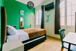 a green bedroom with a bed and a table at The Secret Garden Hostel in Lima