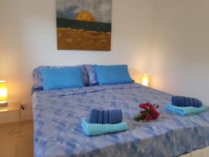 a bed with two blue towels and flowers on it at Hilltop Sea view , Boca Gentil in Willemstad