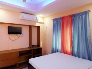 a bedroom with a bed and a tv and curtains at Shopnonir Hotel & Restaurant in Chittagong
