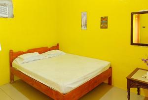 une chambre jaune avec un lit dans une pièce dans l'établissement Erojo's Beach Resort, à Sindangan