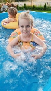 a little girl in a raft in a swimming pool at Szary Domek 4 jacuzzi kominek klimatyzacja jezioro in Trojaczek