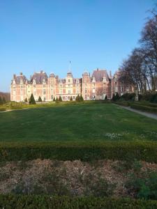 een groot grasveld voor een groot gebouw bij La Nora Jolie in Tocqueville-sur-Eu