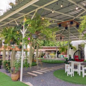 a patio with a table and chairs and palm trees at Evie Mae Camp in Ban Cha-om