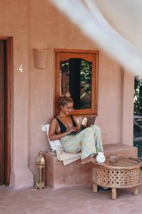 a woman sitting on a window sill with a laptop at Terra Cottages Bali in Uluwatu