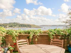 a wooden table and chairs on a patio with a view of the water at Through The Porthole in Falmouth