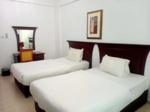 a hotel room with two beds and a mirror at Oasis Hotel Apartment in Ras al Khaimah