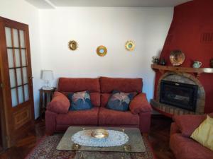 sala de estar con sofá rojo y chimenea en Casa Navacastellanos, en Casarejos
