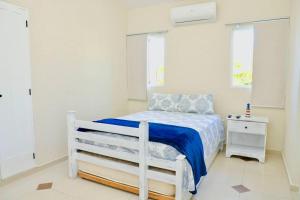 ein Schlafzimmer mit einem weißen Bett mit einer blauen Decke in der Unterkunft New Sunny Villa With Pool Metro Country Club Juan Dolio in La Puntica de Juan Dolio