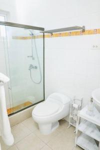 La salle de bains blanche est pourvue d'une douche et de toilettes. dans l'établissement New Sunny Villa With Pool Metro Country Club Juan Dolio, à La Puntica de Juan Dolio