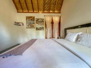 a large white bed in a bedroom with a basketball hoop at Aira Homestay near Pantai Kuta Mandalika Mitra RedDoorz in Bumbang