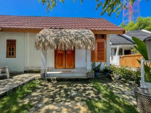 a small white house with a straw roof at Aira Homestay near Pantai Kuta Mandalika Mitra RedDoorz in Bumbang