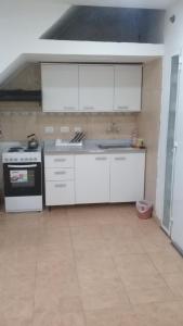 a kitchen with white cabinets and a sink and a stove at 9 de julio in Villa Mercedes
