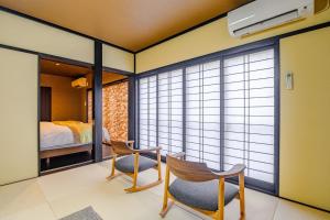 um quarto com duas cadeiras, uma cama e janelas em Hamabe no Yado Asahiya em Himi