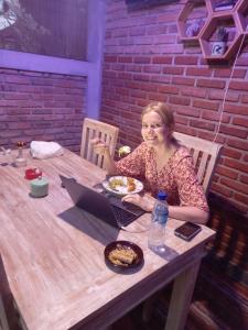 una mujer sentada en una mesa con un plato de comida y un portátil en Dewa Put Guest House en Ubud