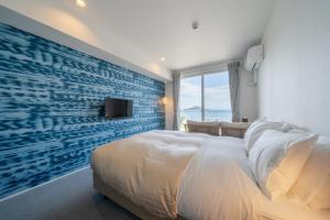 a bedroom with a large bed with a blue accent wall at SETOUCHI SUP RESORT - Ao - in Shodoshima