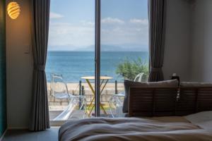 a bedroom with a bed and a view of the ocean at SETOUCHI SUP RESORT - Ao - in Shodoshima