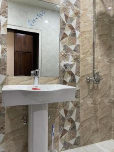 W łazience znajduje się biała umywalka i lustro. w obiekcie Hotel H6 w mieście Rawalpindi