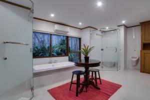 a bathroom with a tub and a table and two stools at Istorya Forest Garden Resort 