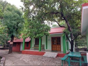 una casa verde y roja con un banco delante en Ranakpur Nature Retreat, en Sādri
