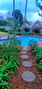 a garden with a walkway next to a swimming pool at Pmb Guest House in Pietermaritzburg