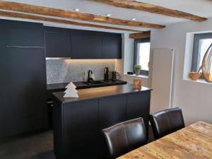 una cocina con armarios negros, fregadero y mesa en Romantic standalone 5 room cottage in Valposchiavo en Poschiavo