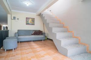 a living room with a staircase and a couch at RedDoorz At Villa Akbar 3 in Batu