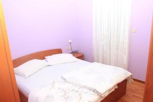 a small bedroom with a bed with white sheets at Apartments by the sea Moscenicka Draga, Opatija - 17381 in Mošćenička Draga