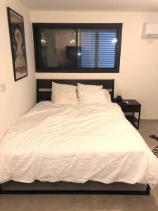 białe łóżko w sypialni z oknem w obiekcie יחידה מושלמת ברמת ישי לזוג או יחיד w mieście Ramat Yishay