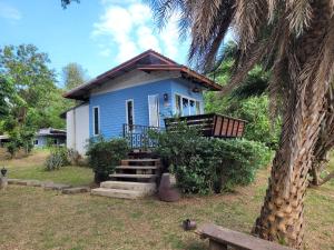 a blue house with a palm tree in front of it at Sawan Srang Nang Kaew in Takhop