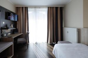 a hotel room with a bed and a desk and a window at Hotel Jellentrup in Münster