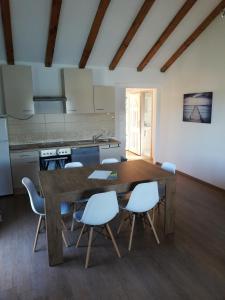 a kitchen with a wooden table and white chairs at Apartments by the sea Supetarska Draga - Donja, Rab - 17201 in Rab