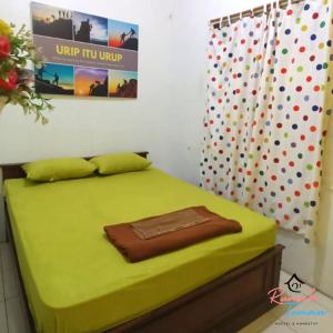 a bedroom with a green bed with at Rumah Teman Hostel in Semarang