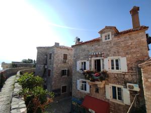 an old stone building with flowers in the window at Guesthouse Bogdanovic in Budva