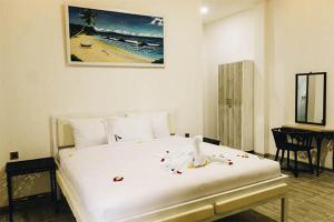 a bedroom with a large white bed and a desk at ImahBC Surfcamp in Tabanan