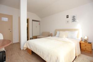 a white bedroom with a large bed and a table at Apartments and rooms with parking space Donje Taboriste, Plitvice - 17486 in Slunj