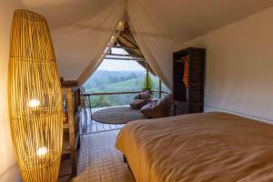 ein Schlafzimmer mit einem Bett in einem Zelt mit Aussicht in der Unterkunft Sanda Plantation Hideaway in Sanda