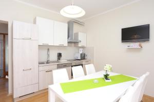 uma cozinha com armários brancos e uma mesa com cadeiras brancas em Apartments for families with children Slunj, Plitvice - 17416 em Slunj
