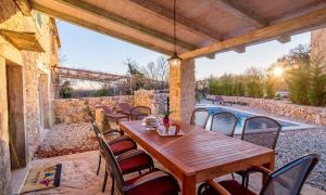 drewniany stół i krzesła na patio z basenem w obiekcie Luxury villa with a swimming pool Garica, Krk - 17469 w mieście Risika