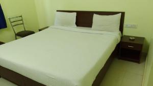 a bedroom with a large white bed and a chair at HOTEL NEW SHELTON SUITES in Bangalore