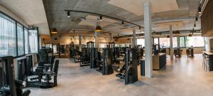 a gym with rows of exercise equipment in a room at LOOM Hotel & Skybar in Eislingen