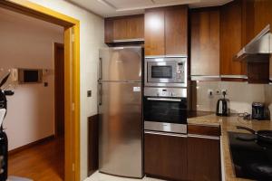 a kitchen with stainless steel appliances and wooden cabinets at Dulive in Dubai