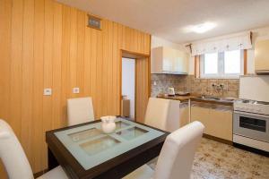 a kitchen with a glass table and white chairs at Apartments by the sea Povlja, Brac - 17472 in Povlja