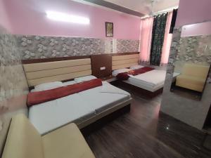a room with two beds and a chair in it at Vidya Guest House in Katra