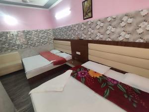 a bedroom with two beds and flowers on the wall at Vidya Guest House in Katra